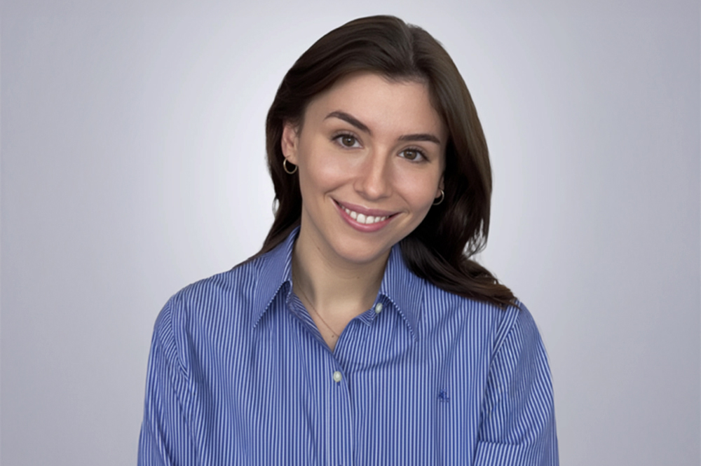 Woman with long hair smiling with a collard shirt in front of blank background