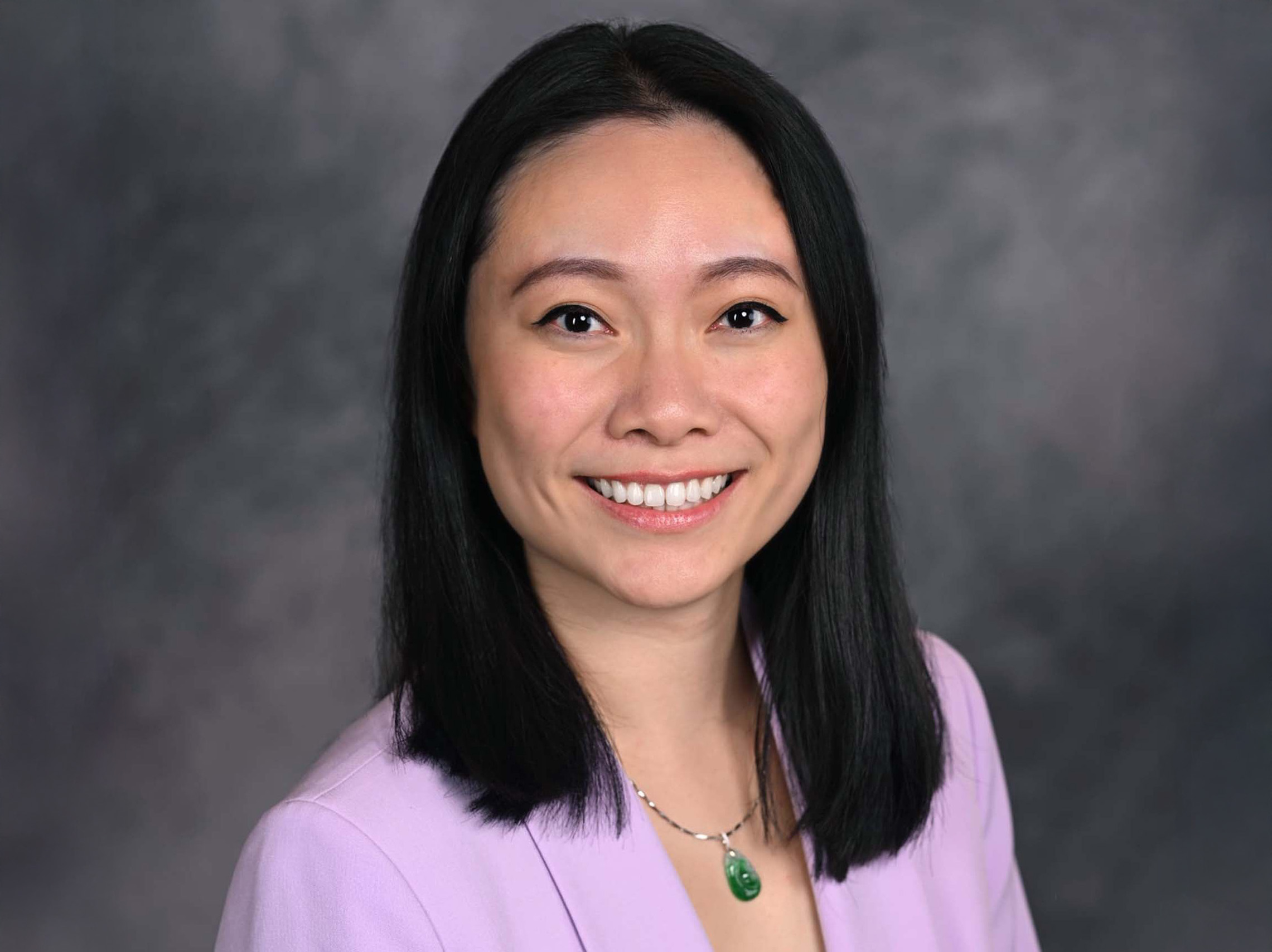Woman with short dark hair and a blazer smiling