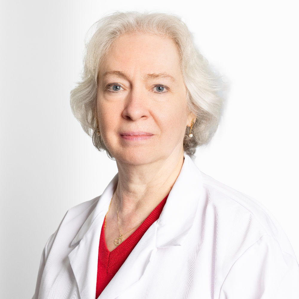 woman with white hair wearing white coat and red shirt