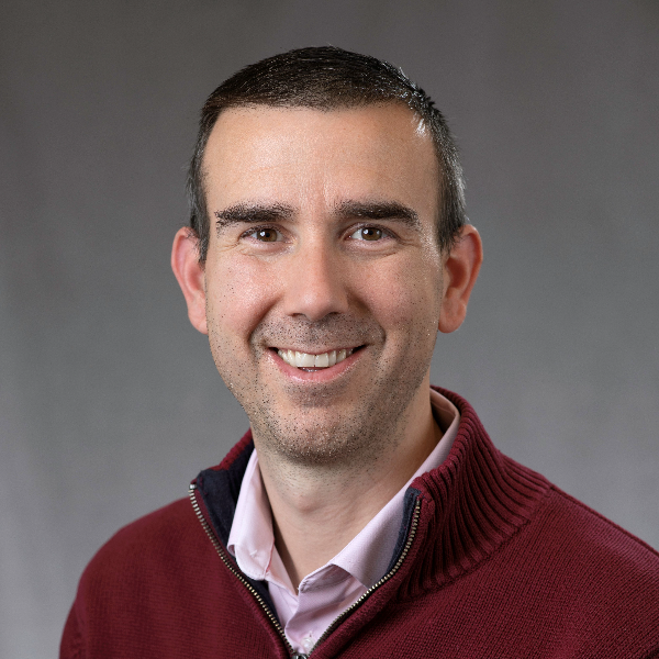 Man posing in red sweater and smiling